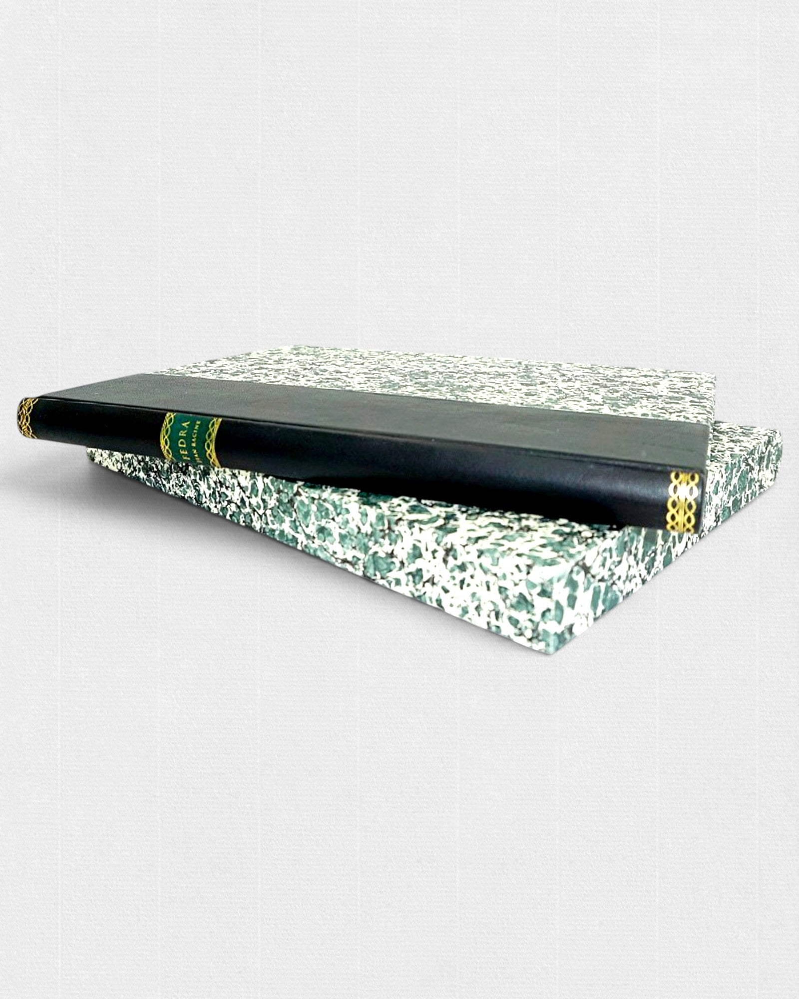 Książka „Fedra” Jeana Racine’a w czarnej skórzanej oprawie ze złoconym grzbietem, ułożona na etui z zielonego marmurkowego papieru, wydanie bibliofilskie.